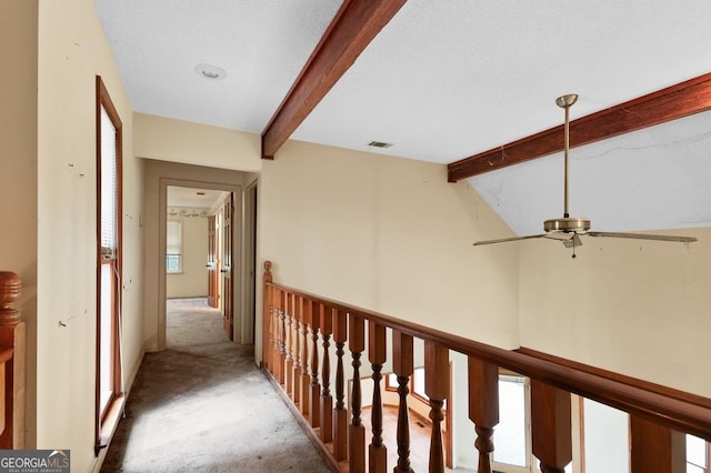 hallway with carpet flooring, vaulted ceiling with beams, and a textured ceiling