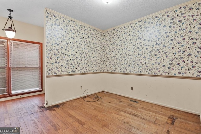 spare room with a textured ceiling, wood-type flooring, and ornamental molding