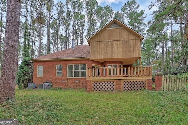 back of house featuring central AC unit, a deck, and a yard