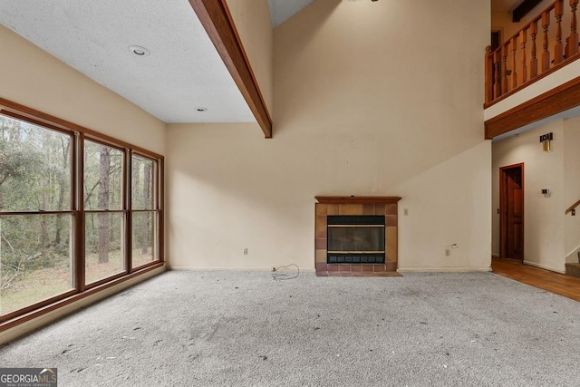 unfurnished living room featuring a fireplace, beam ceiling, carpet flooring, and a high ceiling