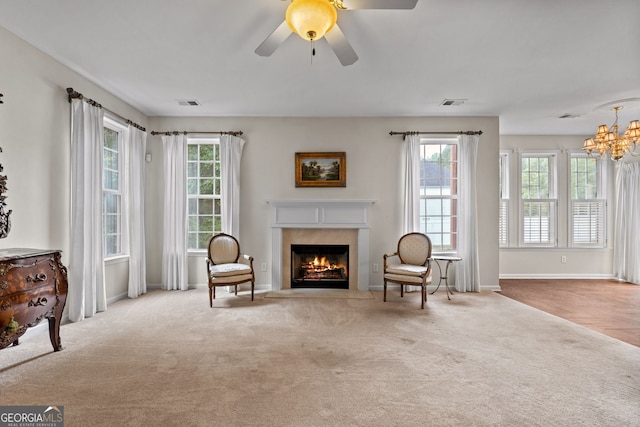 living area with light carpet and ceiling fan with notable chandelier