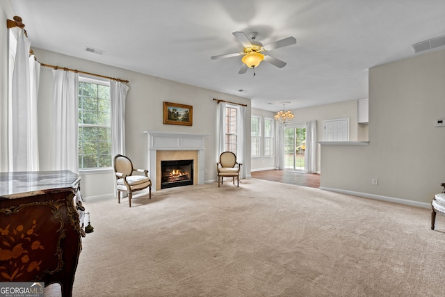 carpeted living room with ceiling fan with notable chandelier and a healthy amount of sunlight