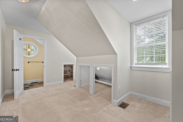 bonus room with lofted ceiling and light colored carpet