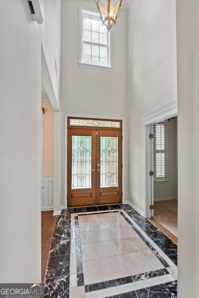 entrance foyer featuring french doors, a chandelier, and a high ceiling