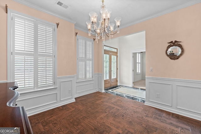 entrance foyer with french doors, ornamental molding, a notable chandelier, and dark parquet flooring