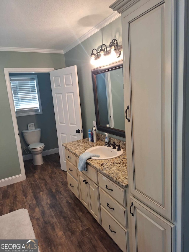 bathroom with hardwood / wood-style floors, vanity, ornamental molding, a textured ceiling, and toilet