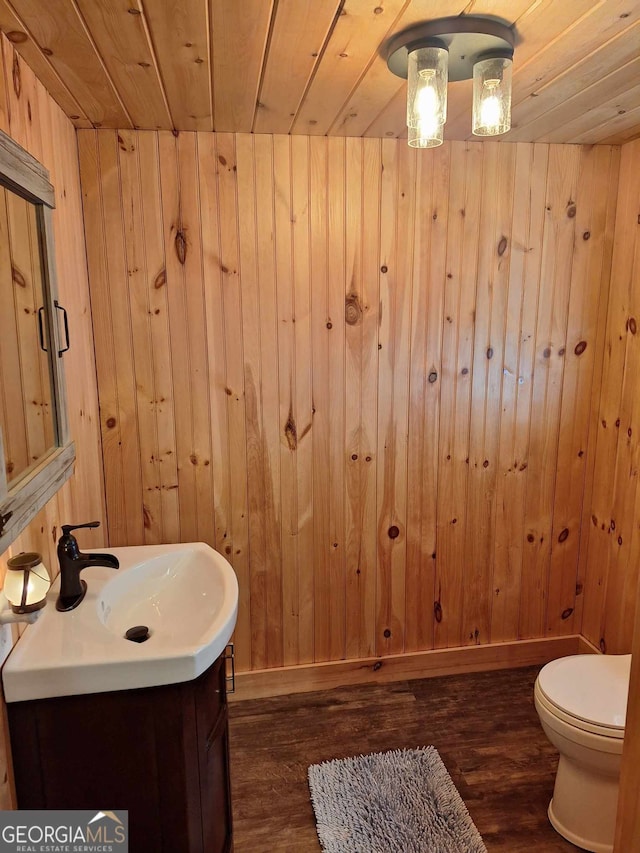 bathroom featuring wood walls, wood-type flooring, vanity, toilet, and wooden ceiling