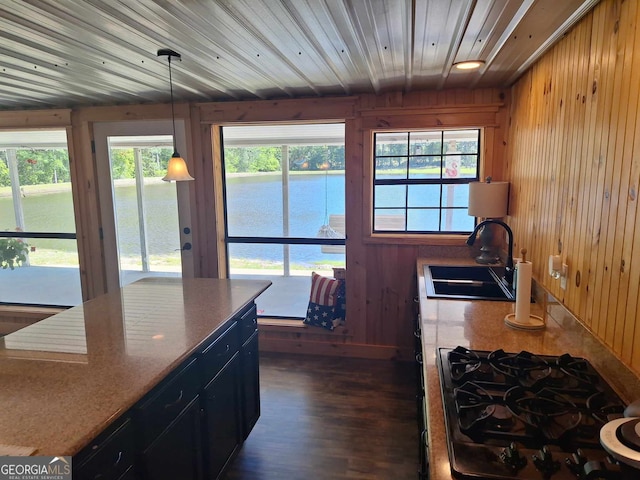 kitchen featuring sink, decorative light fixtures, gas stovetop, and wood walls