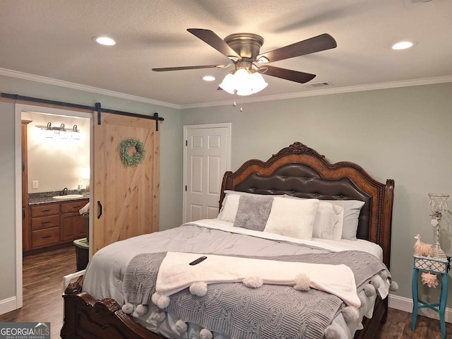 bedroom with crown molding, a barn door, dark hardwood / wood-style flooring, and sink