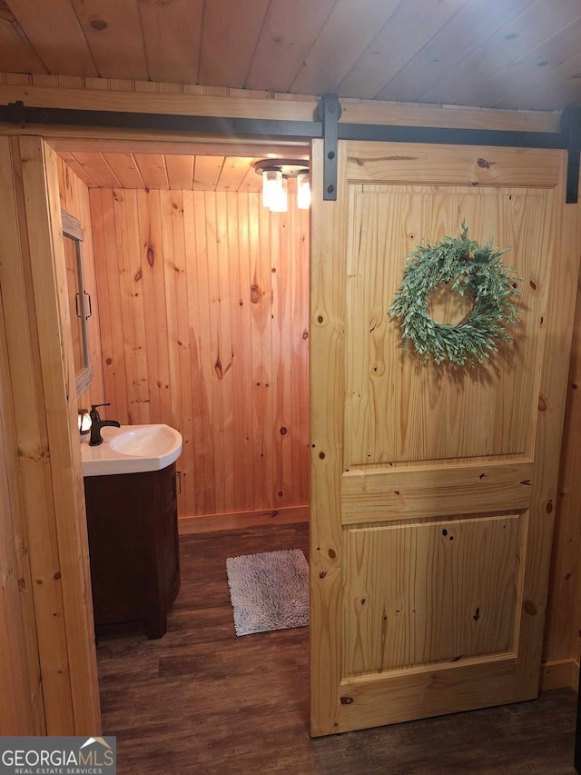 bathroom featuring wood-type flooring, wooden walls, vanity, and wooden ceiling