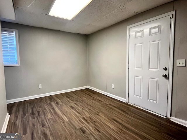 spare room featuring a paneled ceiling and dark hardwood / wood-style flooring