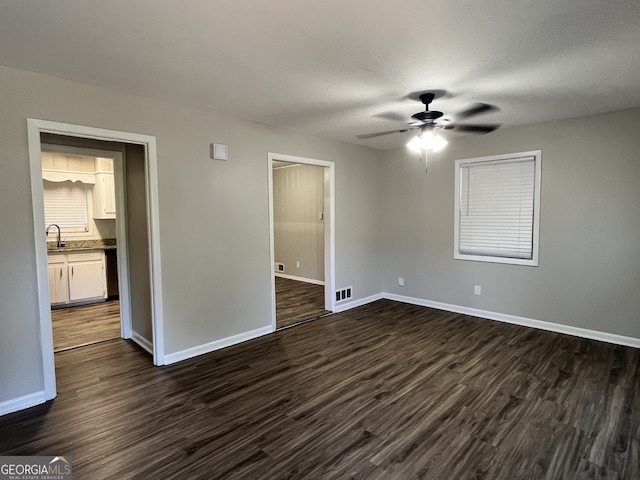 empty room with sink, dark hardwood / wood-style floors, and ceiling fan