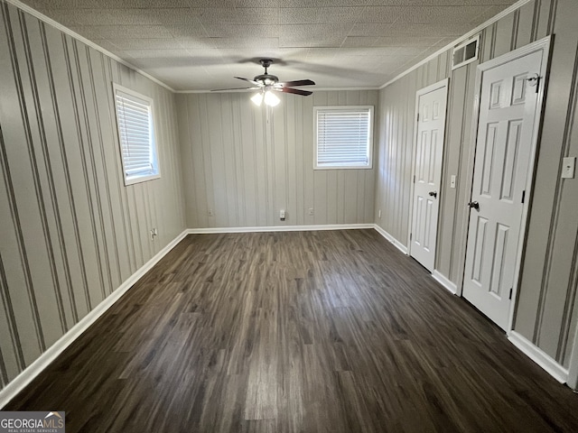 empty room featuring crown molding, ceiling fan, plenty of natural light, and dark hardwood / wood-style flooring