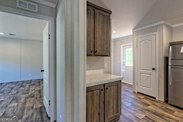 kitchen featuring dark wood-type flooring, crown molding, dark brown cabinets, and stainless steel fridge