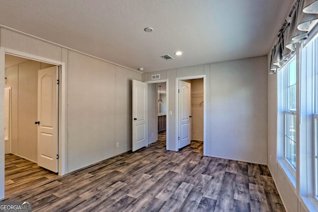 unfurnished bedroom with multiple windows, a closet, and dark hardwood / wood-style floors