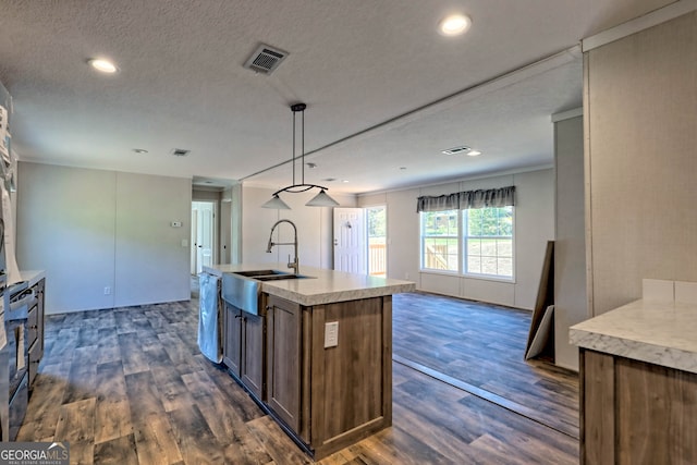 kitchen with a center island with sink, a textured ceiling, dark wood-type flooring, sink, and decorative light fixtures