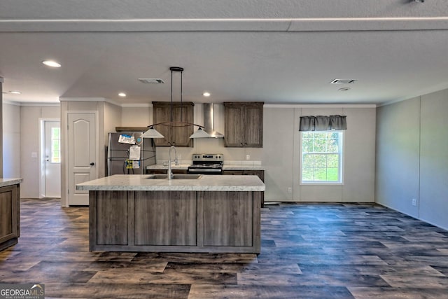 kitchen with stainless steel appliances, sink, a center island with sink, and wall chimney range hood