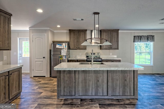 kitchen with appliances with stainless steel finishes, decorative light fixtures, sink, and a center island with sink