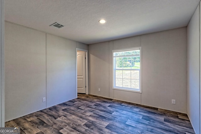 spare room with dark hardwood / wood-style floors and a textured ceiling