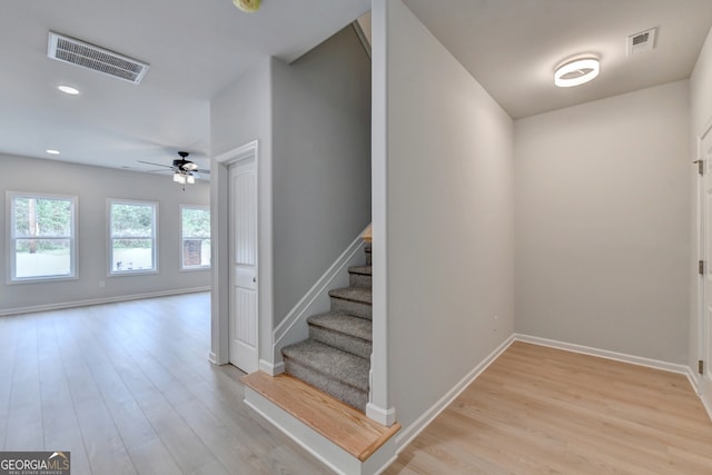 staircase with hardwood / wood-style floors and ceiling fan