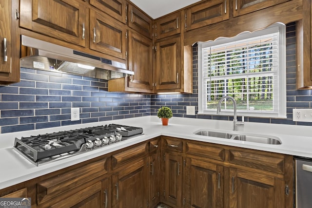 kitchen with decorative backsplash, a sink, appliances with stainless steel finishes, light countertops, and under cabinet range hood