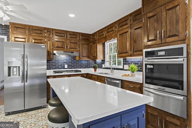 kitchen with stainless steel appliances, a warming drawer, light countertops, and a sink