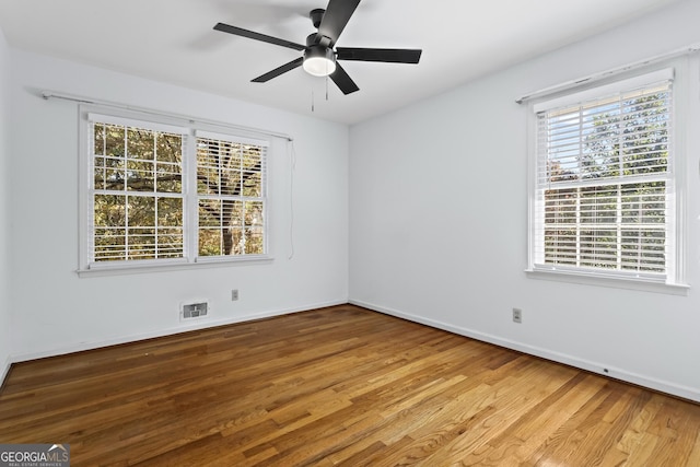 spare room with wood finished floors, visible vents, ceiling fan, and baseboards
