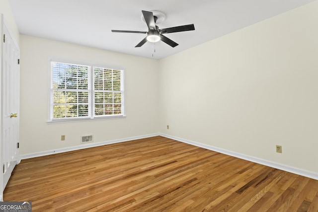 spare room featuring wood finished floors, visible vents, a ceiling fan, and baseboards