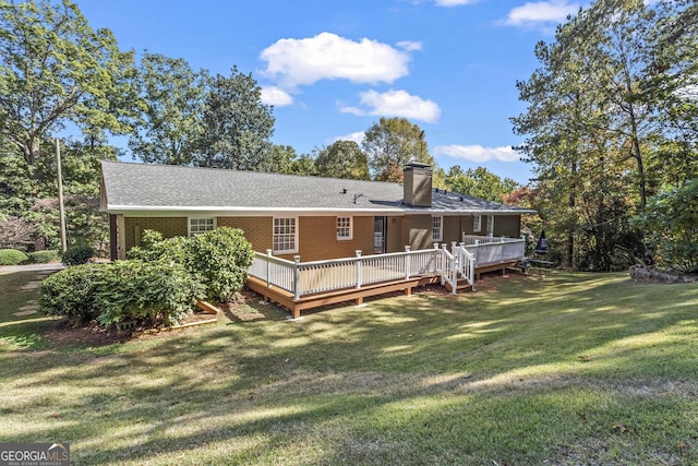 back of house with a wooden deck, a chimney, a shingled roof, a yard, and brick siding