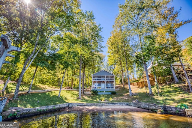 rear view of property with a water view, a sunroom, and a lawn