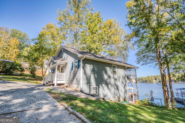 view of home's exterior with a water view, a dock, and a yard