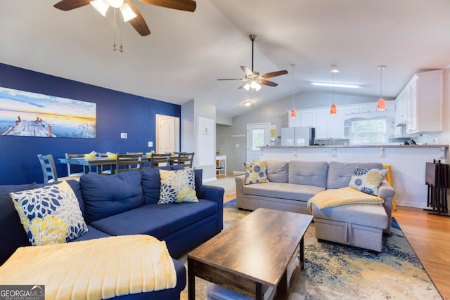 living room with light hardwood / wood-style floors, lofted ceiling, and ceiling fan