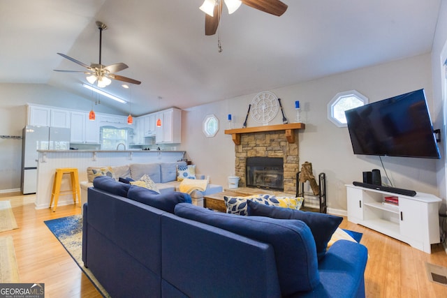 living room with vaulted ceiling, light hardwood / wood-style flooring, a fireplace, and ceiling fan