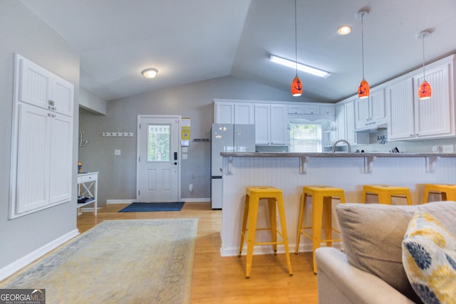 kitchen with white fridge, a kitchen bar, plenty of natural light, and white cabinets