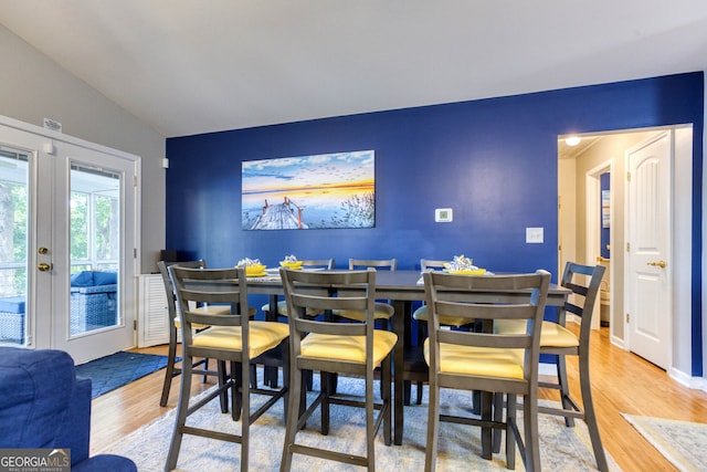 dining room featuring hardwood / wood-style floors, french doors, and vaulted ceiling