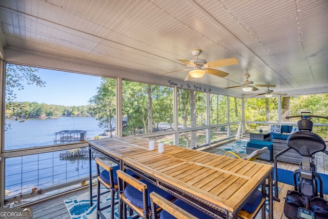 sunroom featuring a water view and ceiling fan