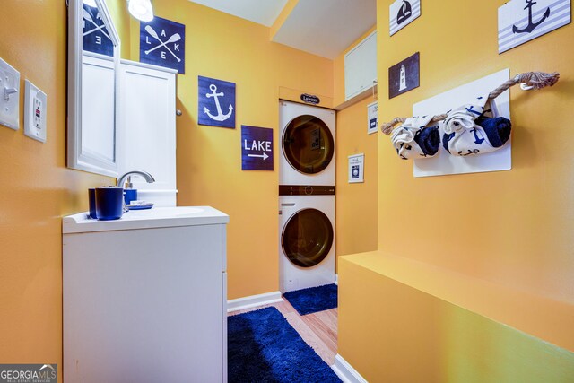 laundry room featuring light hardwood / wood-style floors, stacked washer / dryer, and sink