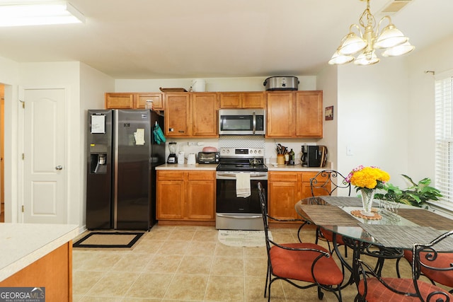 kitchen with tasteful backsplash, light tile patterned flooring, stainless steel appliances, pendant lighting, and an inviting chandelier