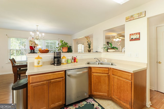 kitchen with sink, light wood-type flooring, kitchen peninsula, pendant lighting, and stainless steel dishwasher