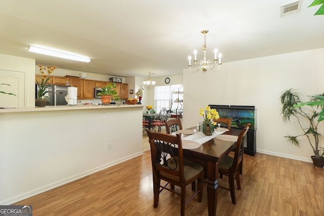 dining space featuring an inviting chandelier and light wood-type flooring