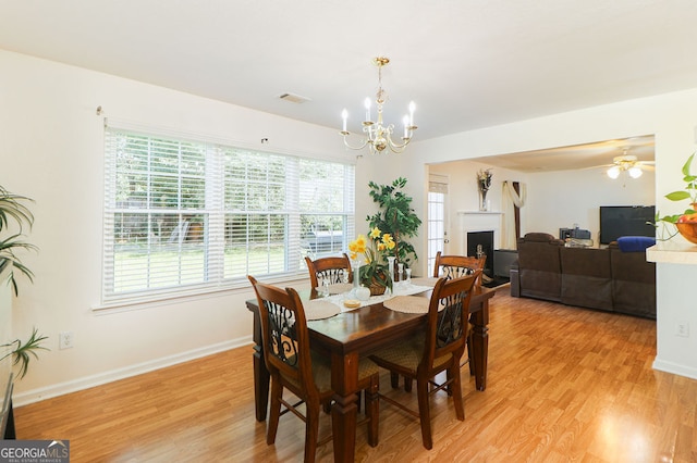 dining space featuring ceiling fan with notable chandelier and light wood-type flooring