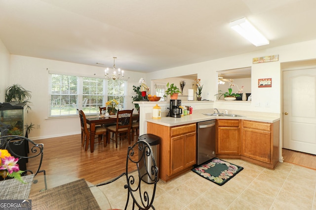 kitchen with hanging light fixtures, an inviting chandelier, stainless steel dishwasher, light wood-type flooring, and sink