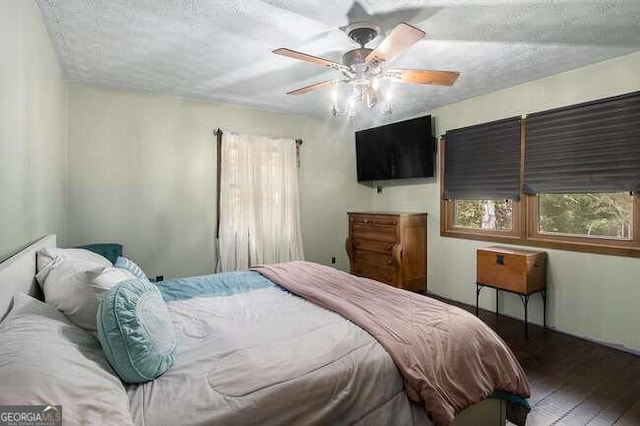 bedroom with ceiling fan, dark hardwood / wood-style flooring, and a textured ceiling