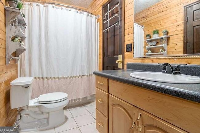 bathroom with tile patterned floors, wood walls, a textured ceiling, toilet, and vanity