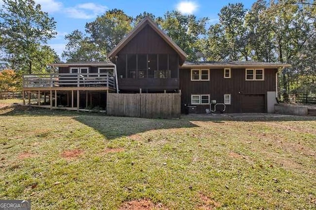 back of house with a deck, a lawn, and a sunroom