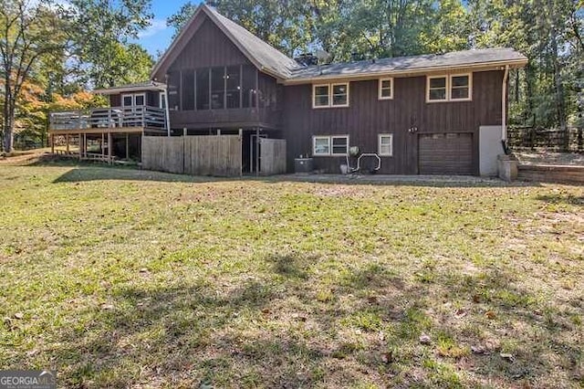 rear view of house with a wooden deck, a sunroom, a yard, and a garage