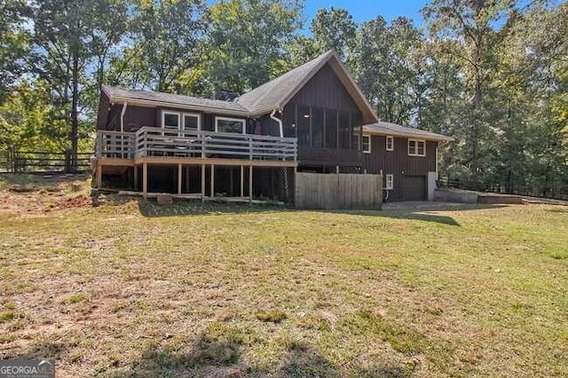 back of house with a sunroom, a deck, and a lawn