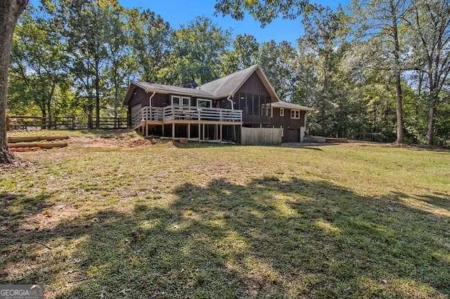 back of property featuring a deck and a lawn