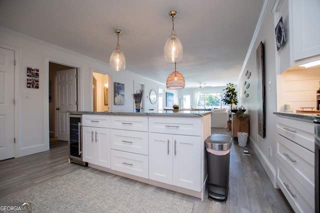 kitchen featuring wine cooler, white cabinetry, light wood-type flooring, and pendant lighting