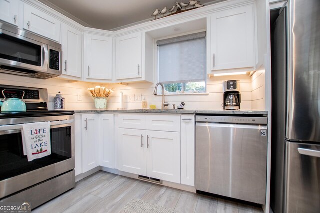 kitchen with ornamental molding, white cabinets, hanging light fixtures, and stainless steel refrigerator